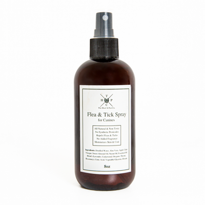 Flea and tick spray for dogs by The Hoof & Paw Co., showing a spray bottle with label and a dog in a natural setting