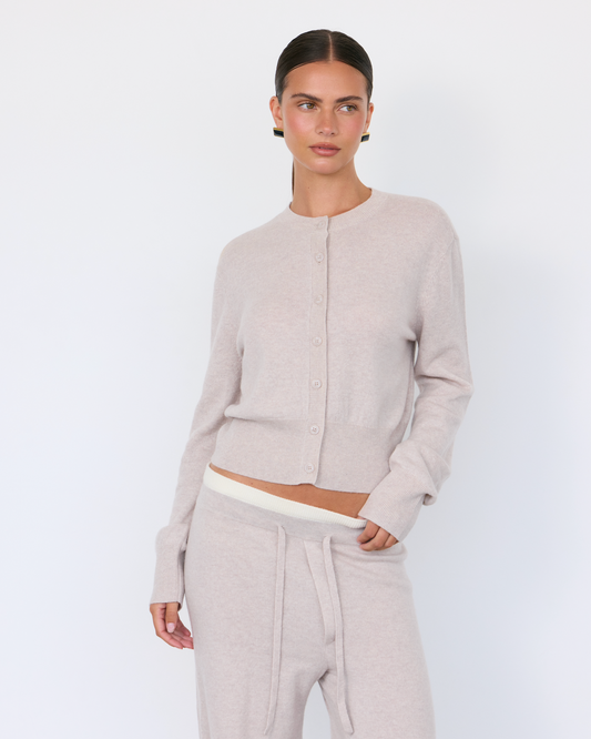 Soft beige Tove Cashmere Cardigan by Artless Forever displayed on a hanger, showcasing its cozy, lightweight knit and relaxed fit.