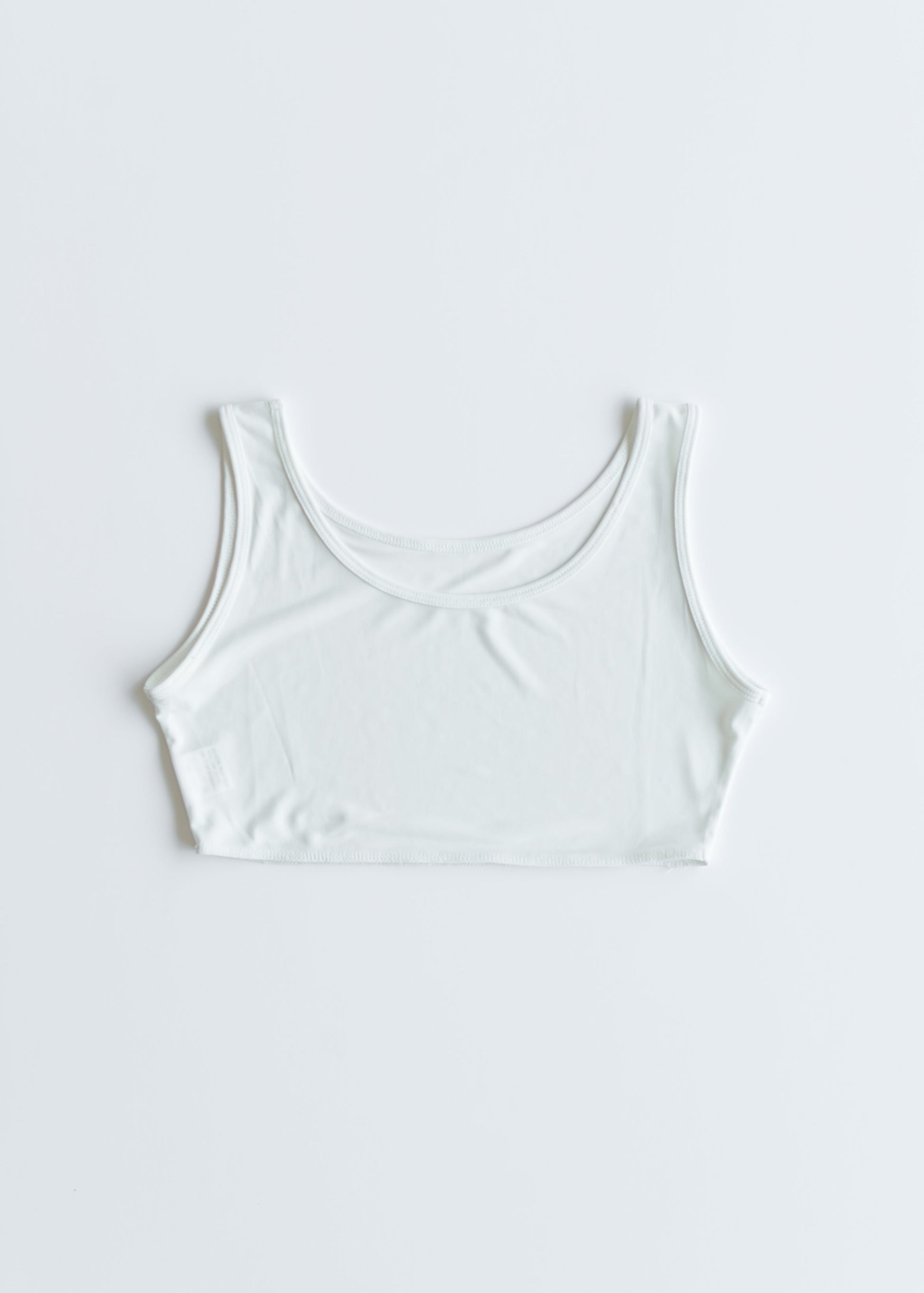 White Dressy Demi Layering Tank from Inherit Co. worn over a top, featuring a sleek, fitted design for versatile layering.