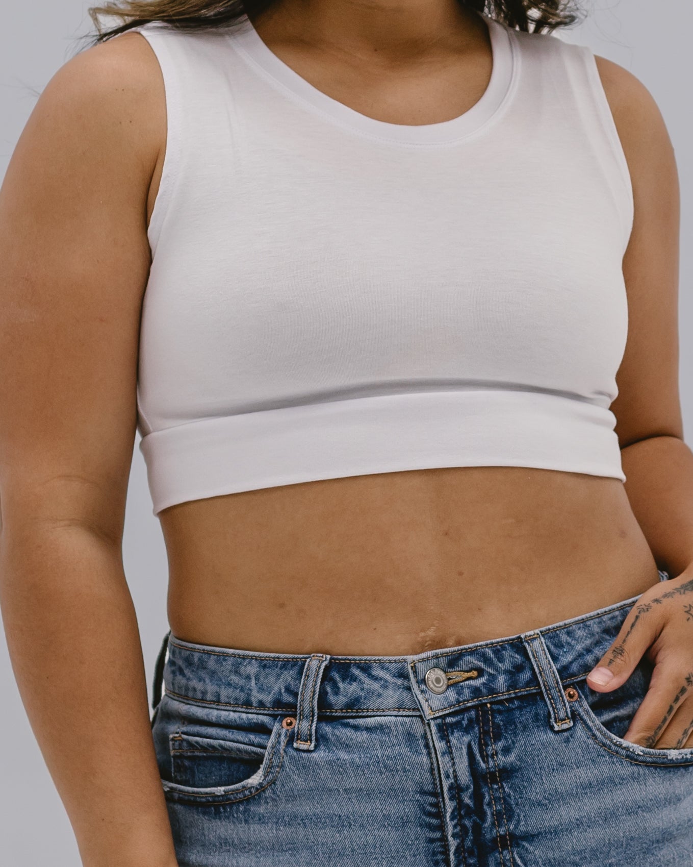 Cream-colored crew neck tank top from HALFTEE Layering Fashions, displayed on a hanger with a close-up of fabric texture.