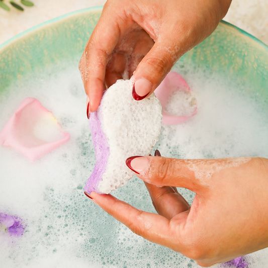 Spongellé Tranquil Mani-Pedi Bundle pedi buffer with lavender scent and floral lavender field background for soothing nail care.